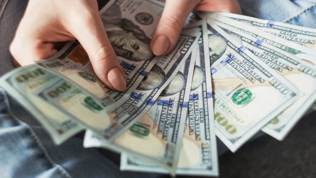 A person holds a bundle of cash, symbolizing financial support from an online loan service.