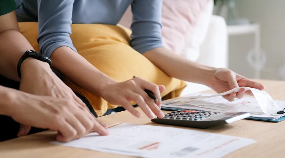 A couple working on a paper with a calculator, preparing a loan application.