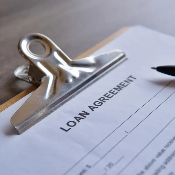 Loan agreement on clipboard with 'Fast loan' written on top, ready for signing.
