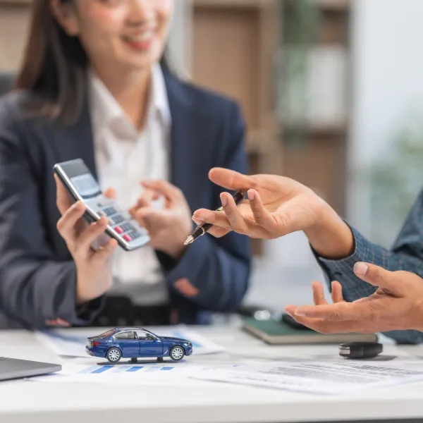 A woman holding a car key and a man holding a calculator, symbolizing fast loan approval.