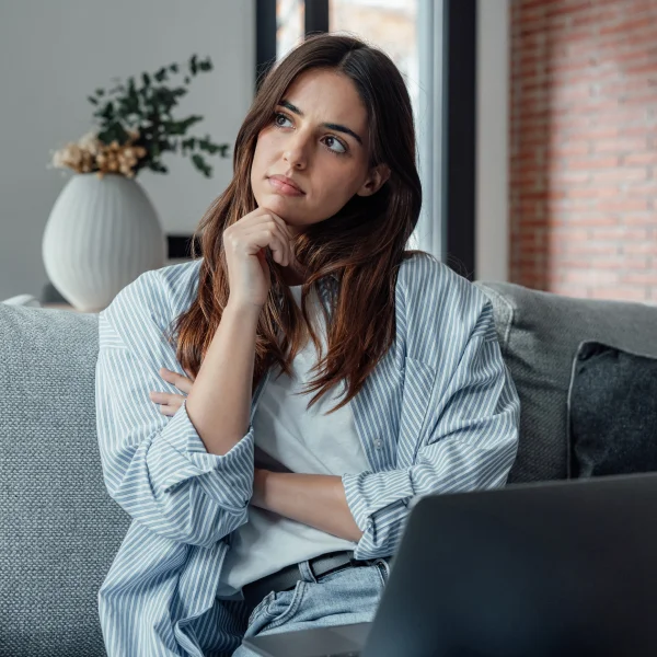 A woman sitting on a couch, using a laptop, symbolizing the concept of loan guarantee and financial support.