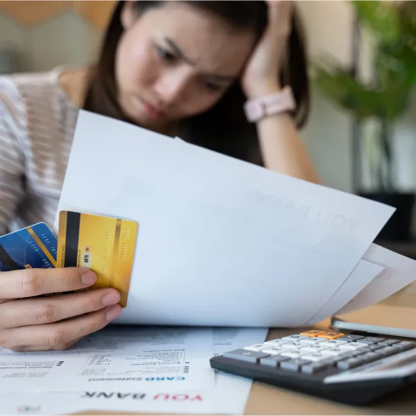 A woman holding a credit card and papers, successfully securing a loan despite having bad credit.
