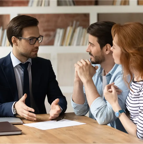 Three people discussing a loan with bad credit with a man at a table.