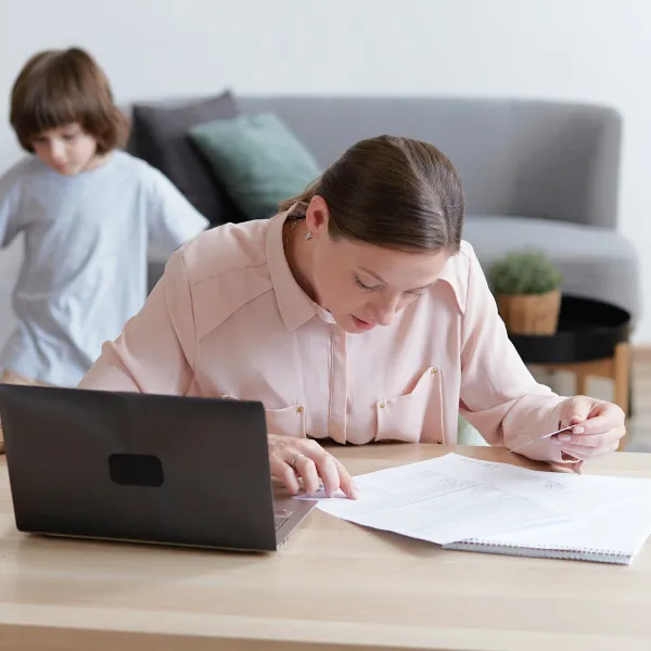 Une femme et un enfant assis à une table avec un ordinateur portable.